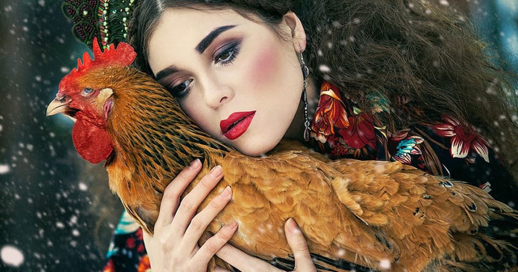 Portrait femme russe avec un coq coloré contre elle, par Maria Karma